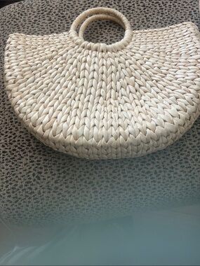 Woven straw bag featuring a semi-circle design with round handle